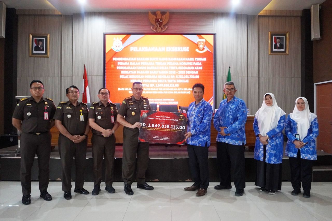 SERAHKAN - Kepala Kejaksaan Negeri (Kejari) Sidoarjo Zaidar Rasepta menyerahkan uang barang bukti korupsi pasang baru senilai Rp 1,8 miliar lebih kepada Dirut Perumda Delta Tirta Sidoarjo, Dwi Hary Soeryadi di Aula Kejari Sidoarjo, Kamis (28/08/2025).