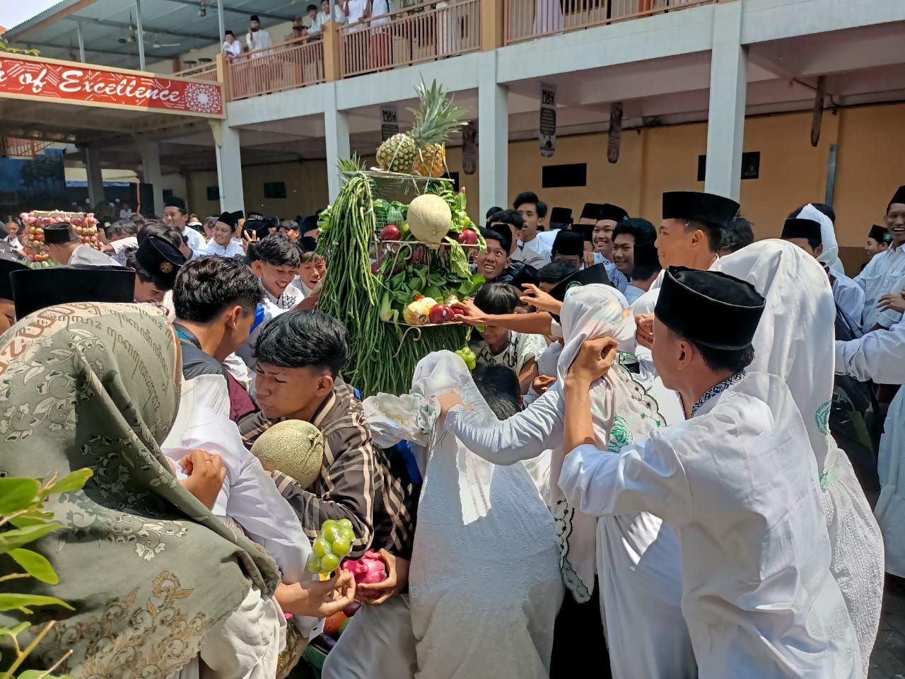 REBUTAN - Sekitar 1.500 siswa dan siswi SMK YPM 8 Sidoarjo berebut lima gunungan buah-buahan dan sayuran di halaman sekolah mereka dalam puncak peringatan Maulid Nabi Muhammad SAW 1447 Hijriyah, Sabtu (06/09/2025).