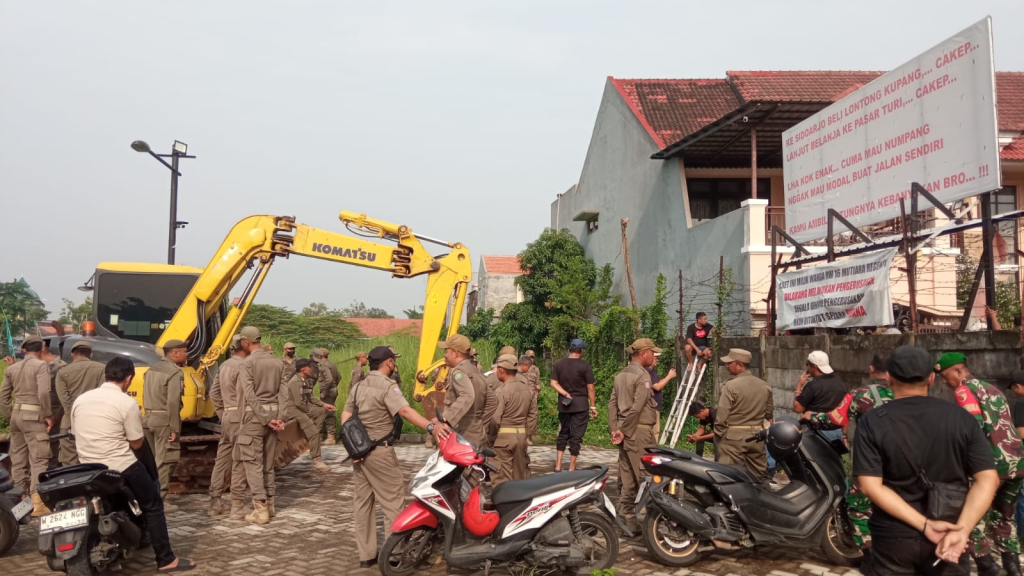 GAGAL - Dinas Perumahan Permukiman Cipta Karya dan Tata Ruang (P2CKTR), Bagian Hukum dan Satpol PP Sidoarjo berusaha membongkar tembok pembatas Perumahan Mutiara Regency dan Perumahan Mutiara City tetapi gagal, Selasa (30/12/2025).