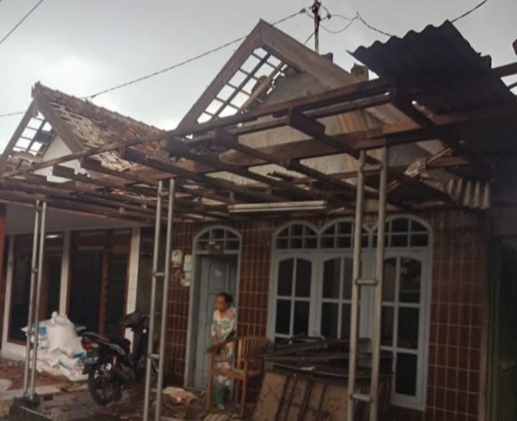 RUSAK - Salah satu rumah warga Desa Prasung, Kecamatan Buduran, Sidoarjo rusak berat dibagian atapnya usai amukan angin kencang, Sabtu (20/12/2025) sore.