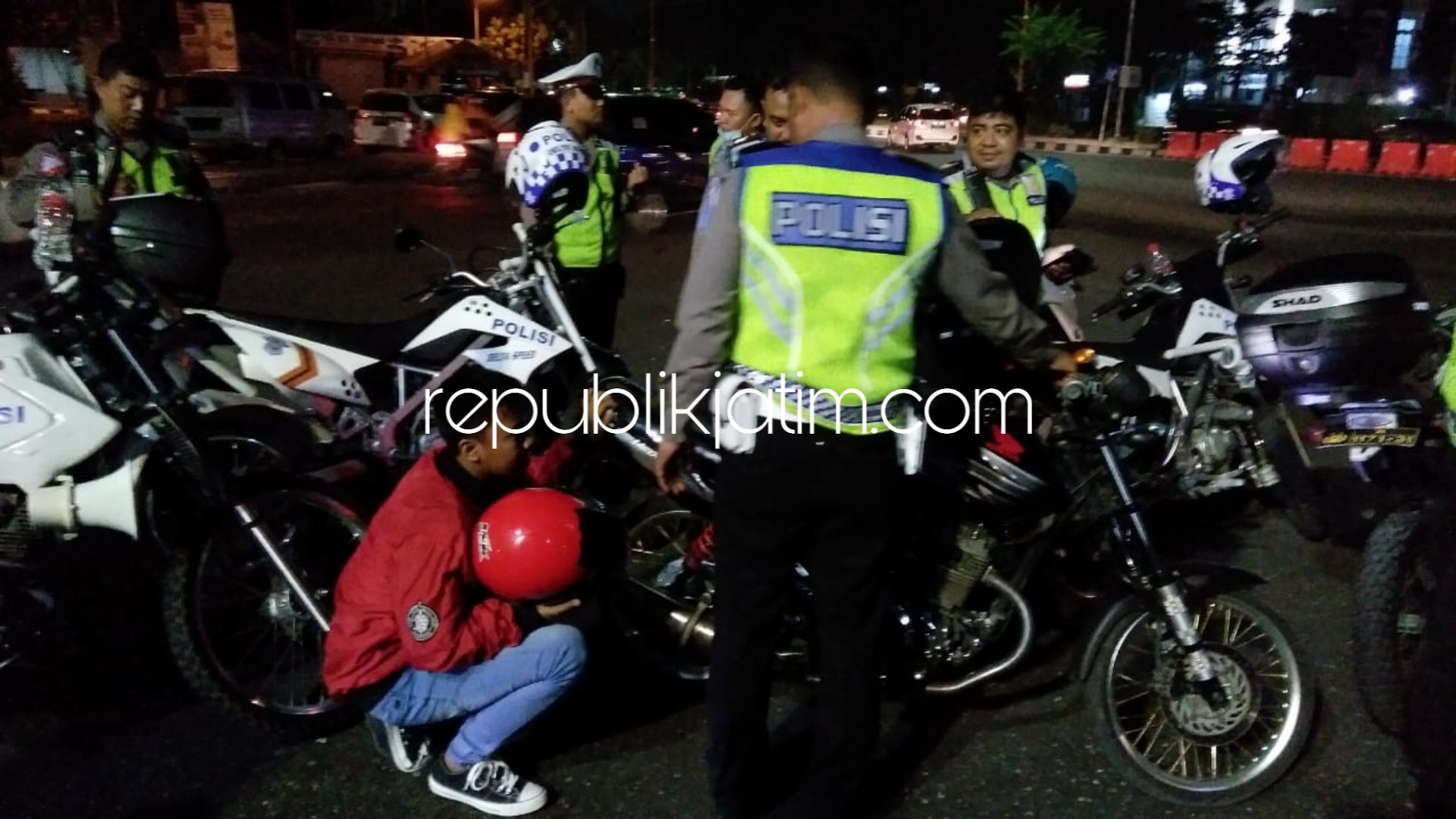 UJI KNALPOT - Salah satu pengendara yang hendak menikmati malam tahun baru ditilang dan diminta mendengarkan suara knalpot brong yang digunakan di samping motornya, Senin (31/12/2018) malam.