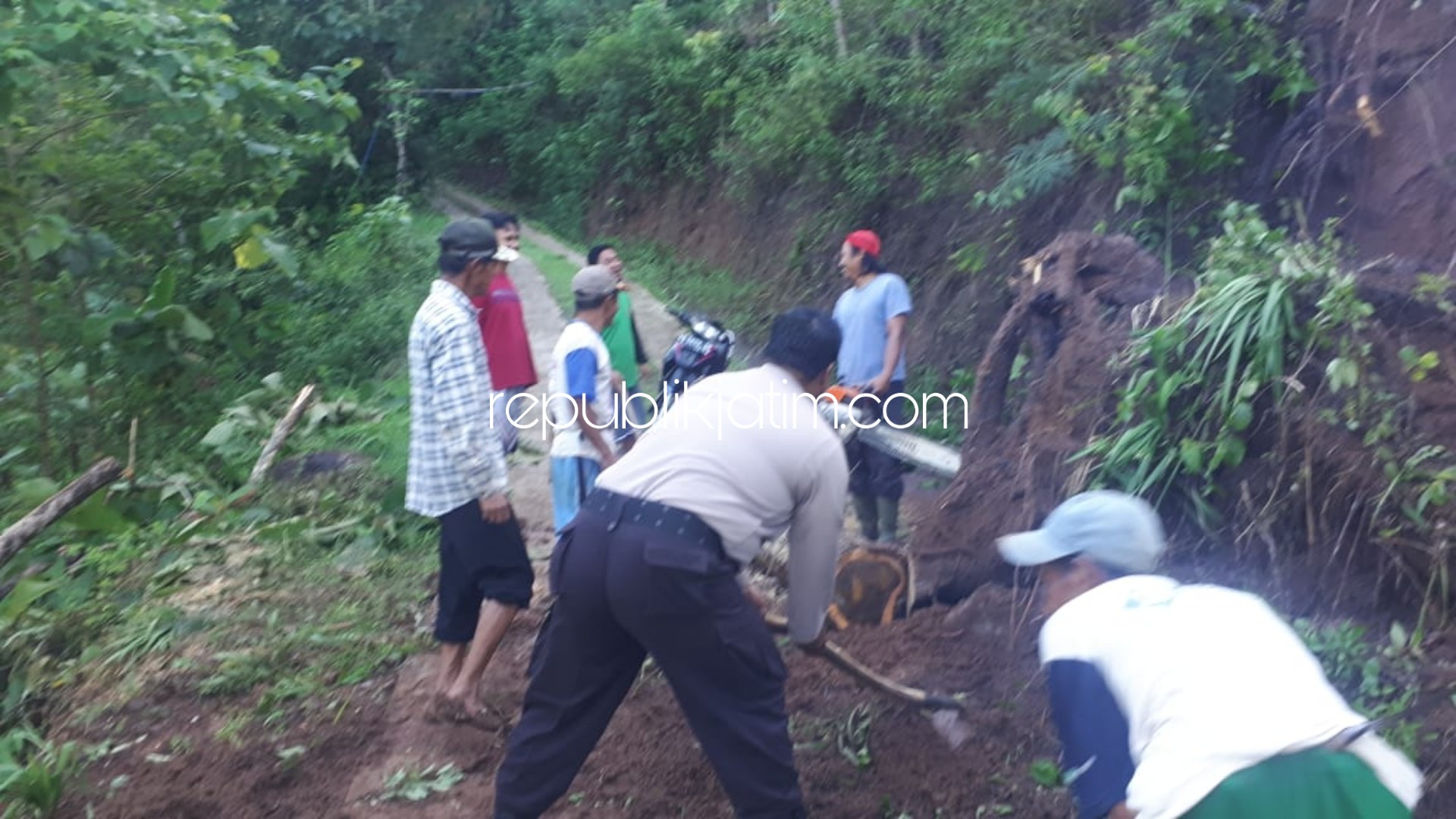 LONGSOR - Warga bersama Pemdes Serag, Kecamatan Pulung serta TNI dan Polri kerjabakti membersihkan material longsor dan mengevakuasi pohon tumbang yang menutup jalan perkampungan akibat longsor, Kamis (02/01/2020) sore.