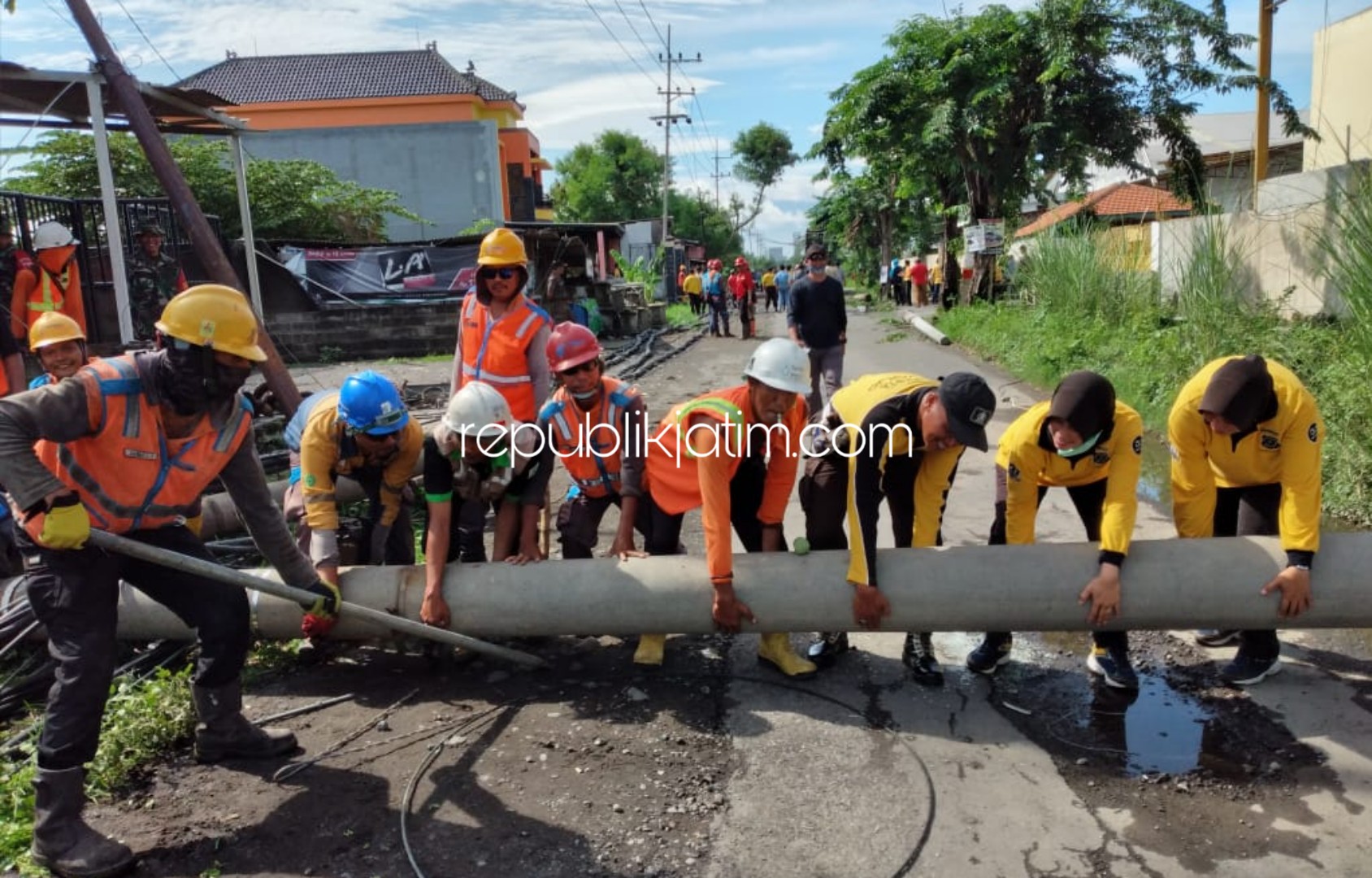 KERJA BAKTI - Sejumlah petugas bekerja bakti membersihkan puing-puing reruntuhan tiang listrik dan pohon yang ambruk di Desa Barengkrajan, Kecamatan Krian, Sidoarjo, Senin (06/01/2020).