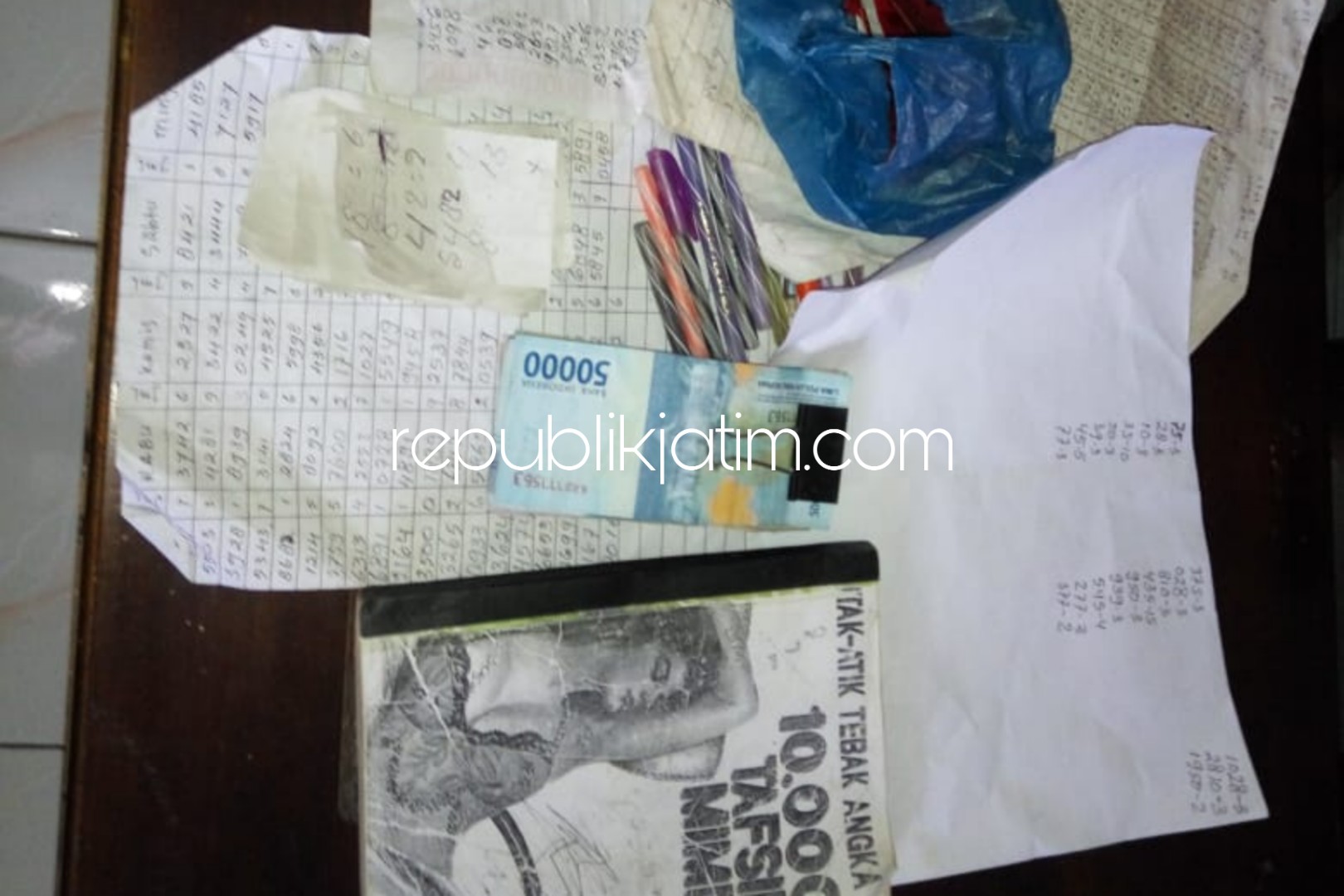 BARANG BUKTI - Petugas Unit Reskrim, Polsek Bungkal mengamankan pengecer judi togel GNI (41) warga Dusun Sambirejo, Desa Kupuk, Kecamatan Bungkal, Ponorogo beserta barang buktinya, Minggu (13/01/2019).