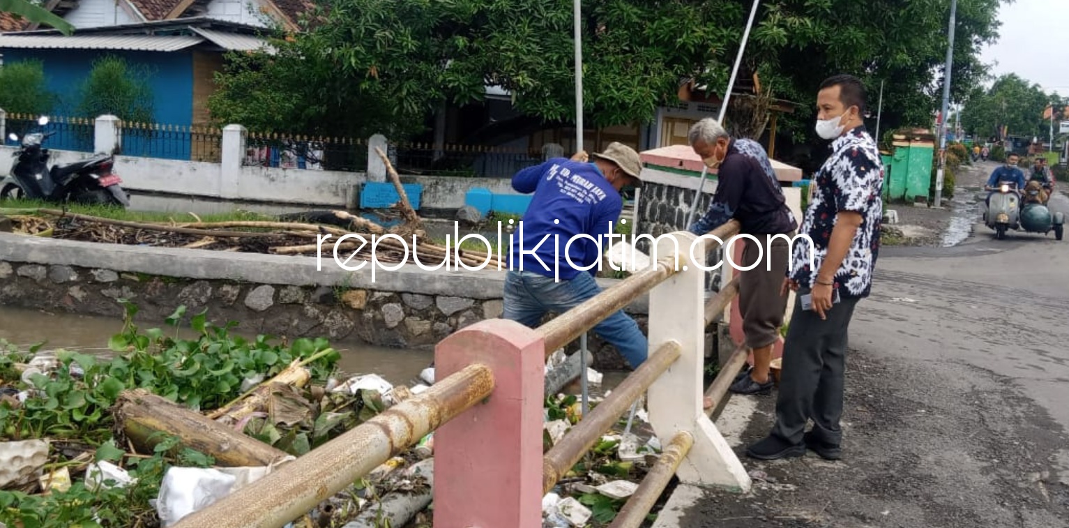 BERSIHKAN - Pj Kepala Desa Candipari, Buari dan Plt Camat Porong, Choirul Anam beserta warga membersihkan sampah dan tanaman eceng gondok yang menumpuk pada jembatan sungai desa setempat yang memicu banjir, Selasa (19/01/2021).