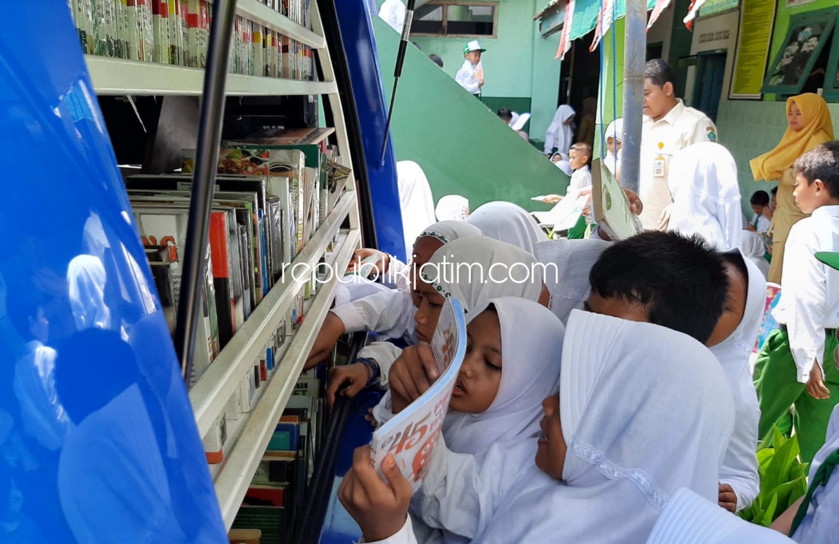 REBUTAN - Puluhan siswa dan siswi MI Nurul Huda Balongbendo, Sidoarjo berebut buku dari Perpustakaan Keliling di halaman sekolahnya, Senin (20/01/2020).