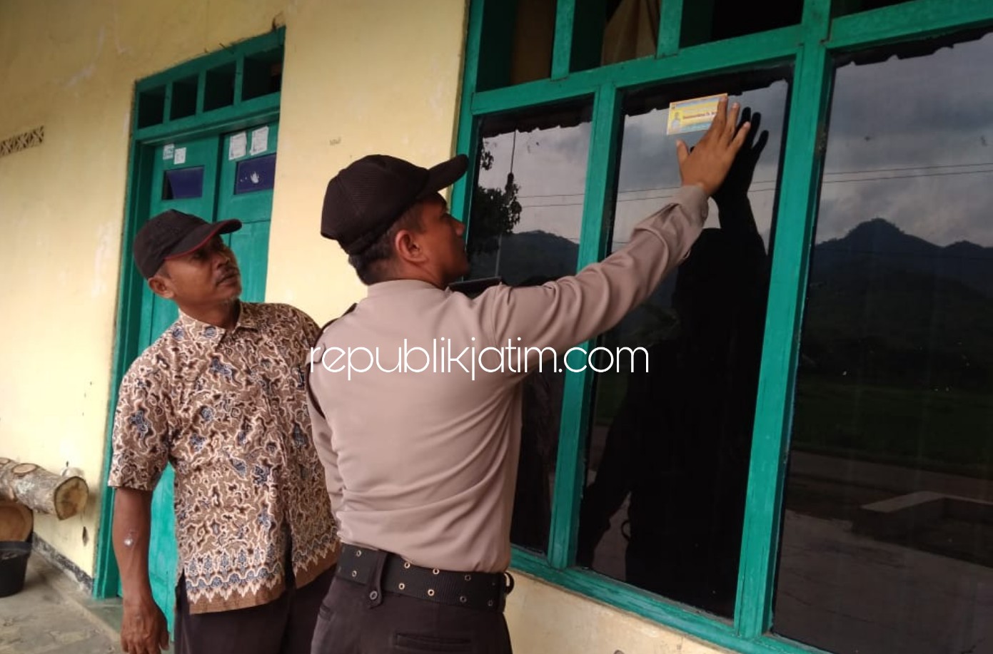 TEMPEL STIKER- Bripka Iswahyudi saat menempelkan stiker berisi poto dan noner HP di rumah rumah warga dan tempat umum di desa binaannya Desa Munggu, Kecamatan Bungkal, Ponorogo Kamis (30/01/2020).