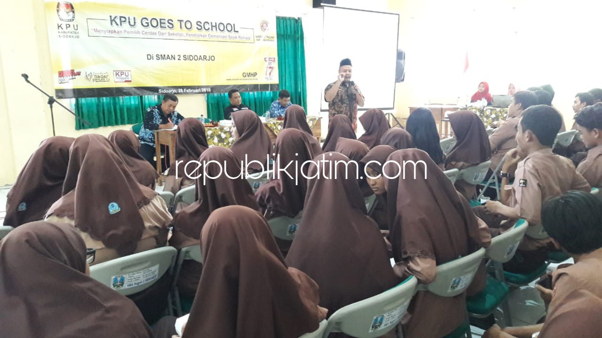 SOSIALISASI - Komisioner KPU Sidoarjo, M Iskak bersama Ketua Karang Taruna Sidoarjo, Imam Syafii didampingi Waka Kesiswaan SMAN 2 Sidoarjo, Diduk memberikan sosialisasi pendidikan politik untuk siswa kelas 12 sebagai pemilih pemula, Kamis (28/02/2019).