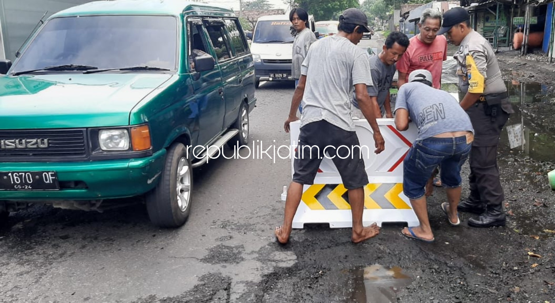 TAMBAL - Puluhan warga Desa Bakungtemenggungan, Kecamatan Balongbendo, Sidoarjo bekerja bakti bersama anggota Polsek Balongbendo menambal dan memberi water barrier di Jalan Propinsi yang berlubang, Minggu (22/03/2020).