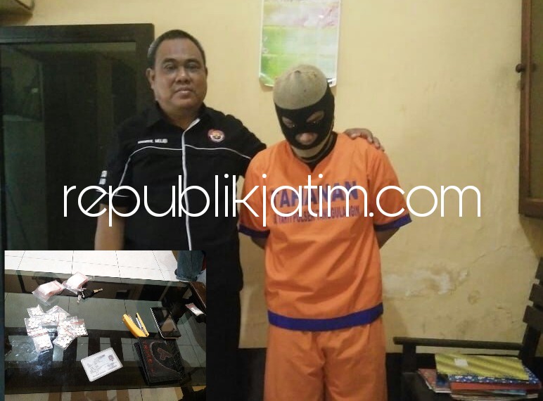 PENGEDAR - Tersangka pengedar pil koplo, Aris Setiawan tertunduk lesu didampingi petugas Polsek Tanggulangin bersama 10 kantong plastik berisi 10 butir, dua kantong palstik berisi plastik kecil, serta uang sebesar Rp 125.000, Senin (21/05/2018).