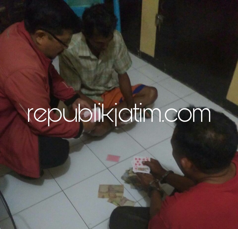 PENJUDI - Tersangka penjudi remi, Sugianto (kanan) dan Adim didampingi petugas Polsek Porong beserta barang buktinya, Selasa (22/05/2018).
