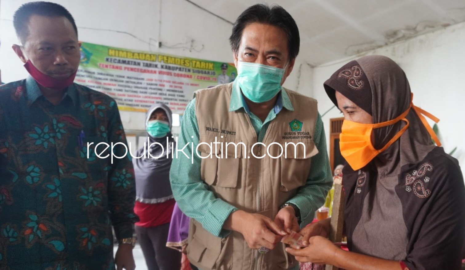 SERAHKAN - Plt Bupati Sidoarjo, Nur Ahmad Syaifuddin didampingi Kepala Dinsos Pemkab Sidoarjo, Tirto Adi secara simbolis menyerahkan bantuan Rp 200.000 kepada keluarga kurang mampu di wilayah Kecamatan Tarik, Sabtu (20/06/2020).