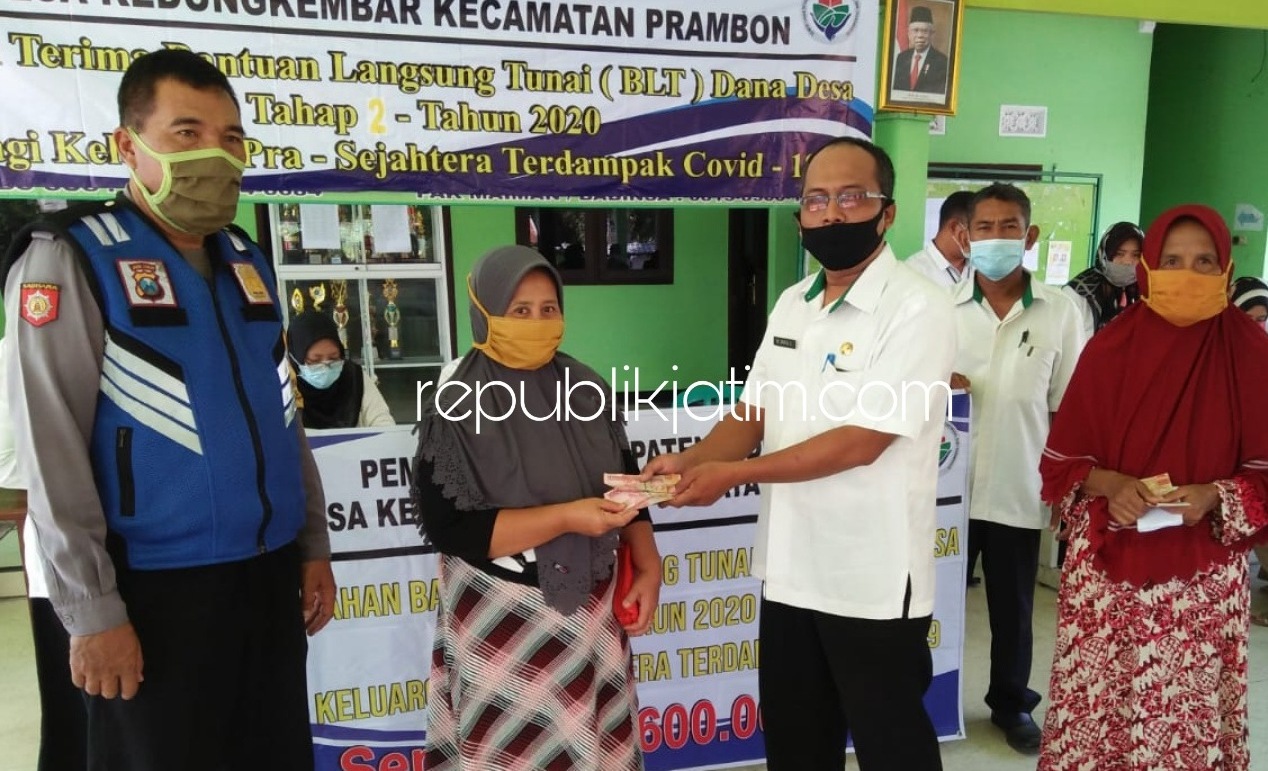 SERAHKAN - Pj Kepala Desa Kedungkembar, Kecamatan Prambon, Sidoarjo, M Saiful C secara simbolis menyerahkan Bantuan Langsung Tunai Dana Desa (BLT DD) kepada 61 warganya di balai desa setempat, Rabu (24/06/2020).