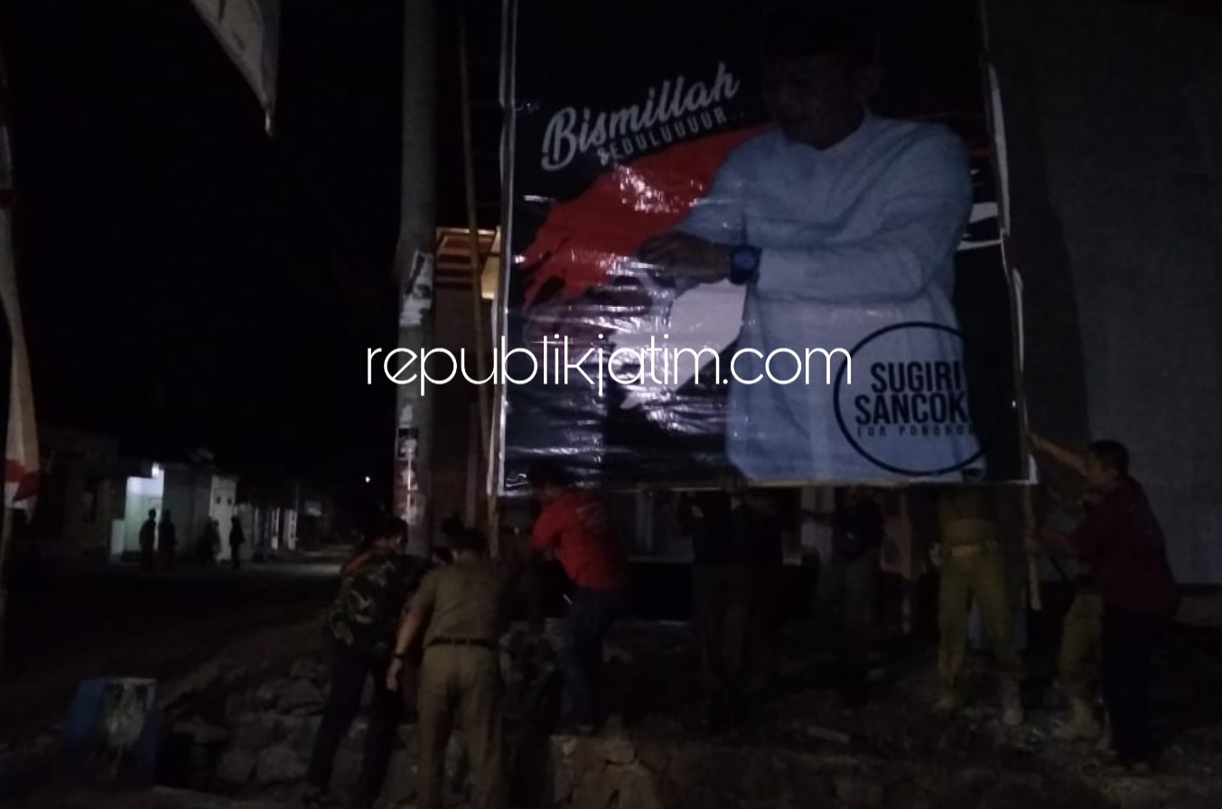 PASANG BALIHO - Akhirnya anggota Satpol PP Ponorogo memasang kembali baliho yang dilepas pagi hari ke tempat semula di sejumlah titik di Ponorogo, Rabu (22/07/2020) malam. 