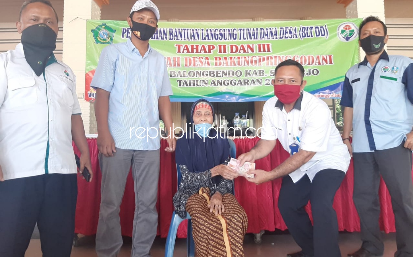 BANTUAN - Pj Kades Bakungpringgondani, Riadi didampingi Camat Balongbendo, Puguh Santoso menyerahkan bantuan BLT DD Tahap II dan III untuk 110 Keluarga Penerima Manfaat (KPM) di balai desa setempat, Rabu (29/07/2020).
