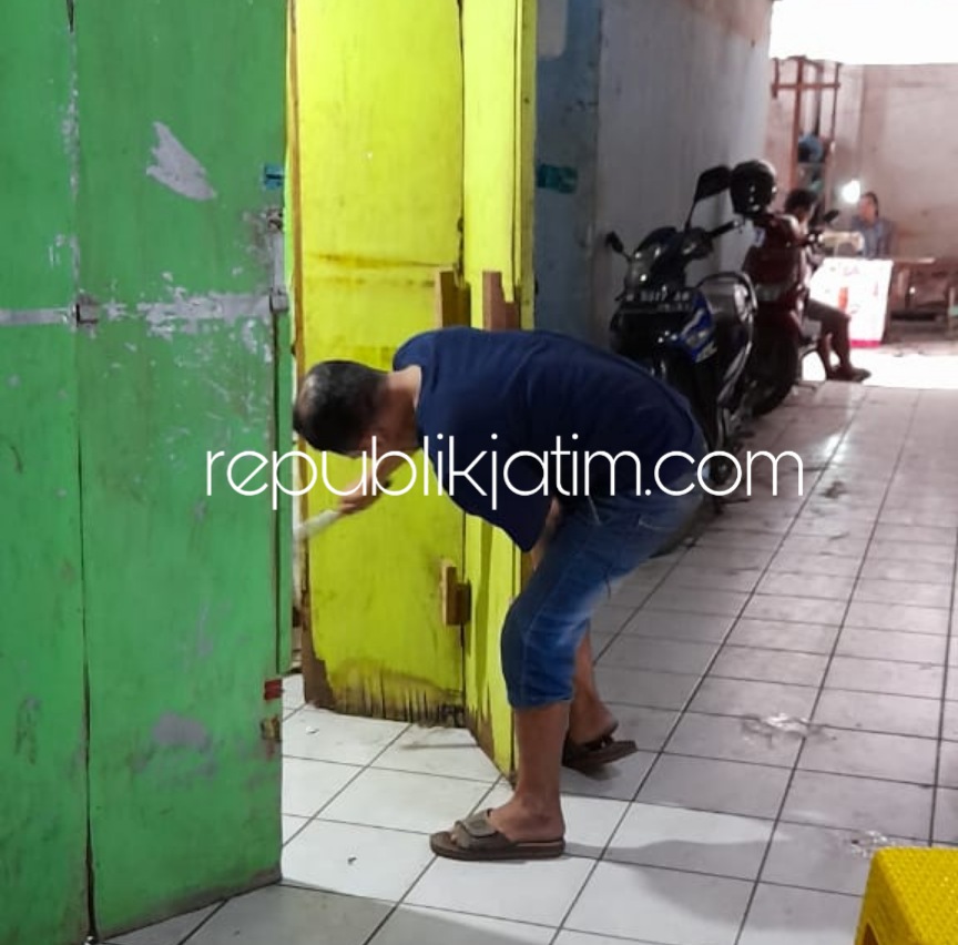 PERBAIKI - Korban pencurian Agus memperbaiki pintu di stan Warkop miliknya yang ada di Pasar Krian, Sidoarjo usai dibobol kawanan pencuri, Senin (10/08/2020).
