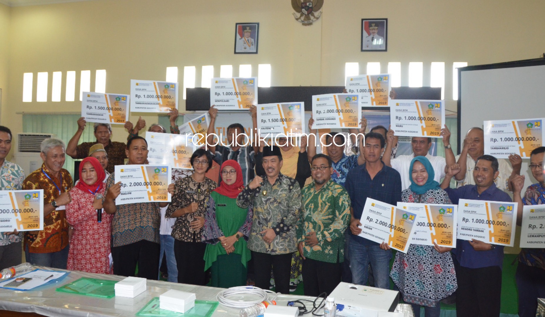 SERAHKAN - Wabup Sidoarjo, Nur Ahmad Syaifuddin menyerahkan bantuan Rp 21,5 miliar program Kota Tanpa Kumuh (Kotaku) di Kantor Dinas Pemerintahan Desa Pemkab Sidoarjo, Selasa (27/08/2019).