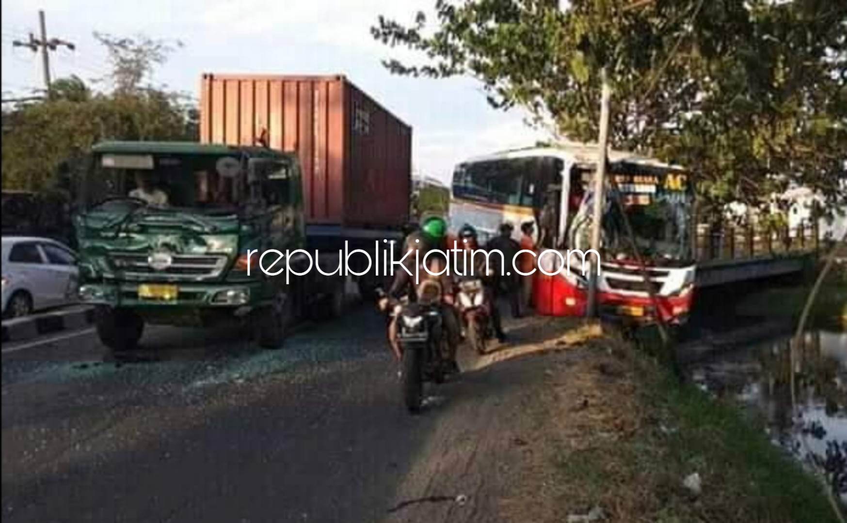 TERSANGKUT - Bus Harapan Jaya bernopol AG 7894 UR tampak tersangkut tiang PJU di JL Raya Desa Sidorejo, Kecamatan Krian, Sidoarjo usai tabrakan beruntung dengan 2 truk trailer, Jumat (02/11/2018) petang.