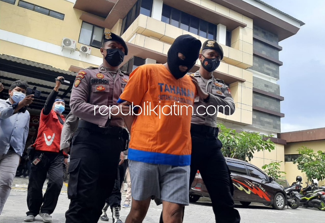 GELANDANG - Tersangka MWS (40) warga Waru digelandang petugas Polresta Sidoarjo berserta barang buktinya saat dipamerkan ke media di Polresta Sidoarjo, Senin (17/01/2022).