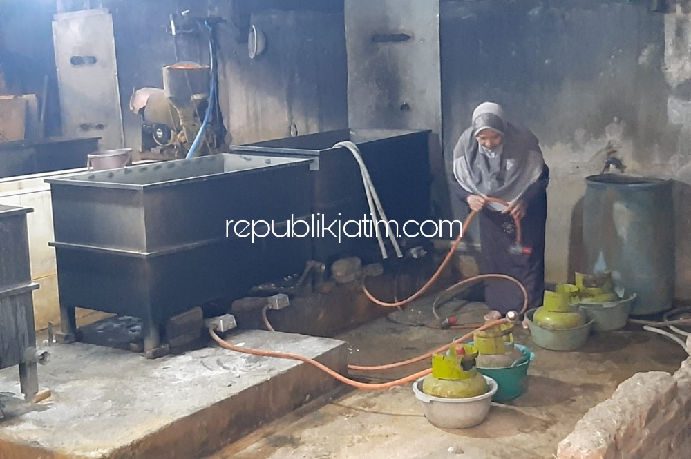 MOGOK - Salah seorang produsen tempe di sentra pembuatan tempe Desa Sedenganmijen, Kecamatan Krian, Sidoarjo membersihkan di tempat dan mesin produksi dibelakang rumahnya karena mogok produksi, Selasa (22/02/2022).