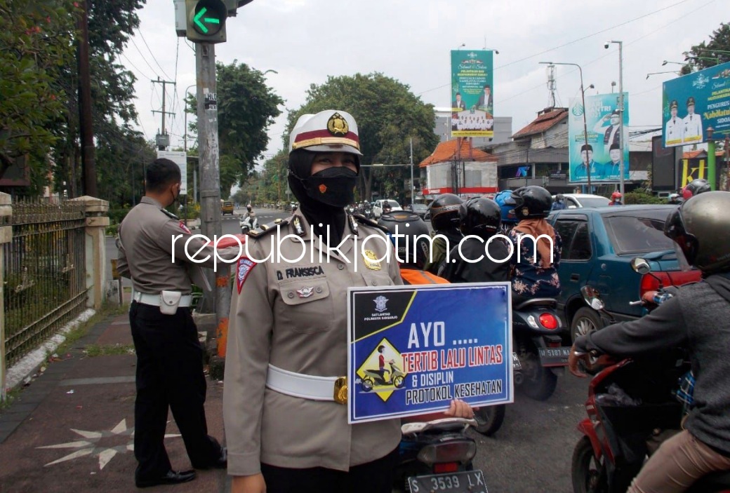 HIMBAUAN - Anggota Satuan Lantas Polresta Sidoarjo sosialisasi himbauan tertib berlalu lintas dan patuhi protokol kesehatan pencegahan Covid-19 ke sejumlah pengendara yang melintas di traffic light JL A Yani, Sidoarjo, Rabu (02/03/2022).