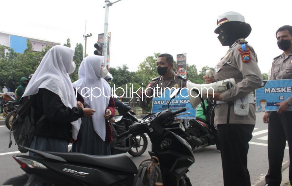 HIMBAUAN - Sejumlah petugas Lantas, Polresta Sidoarjo memberi himbauan tertib berlalu lintas dan patuhi protokol kesehatan pencegahan Covid-19 ke pengendara yang melintas di traffic light JL Raya Pagerwojo, Sidoarjo, Jumat (04/03/2022).