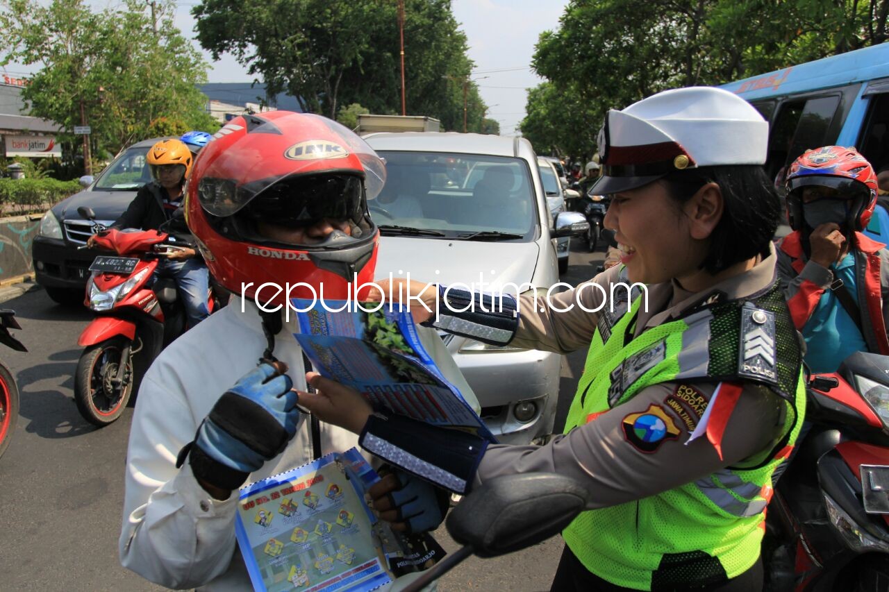 BAGI BROSUR - Sejumlah anggota Satuan Lantas, Polresta Sidoarjo membagikan brosur keselamatan berkendara di perempatan alun-alun Sidoarjo, Selasa (06/03/2018).